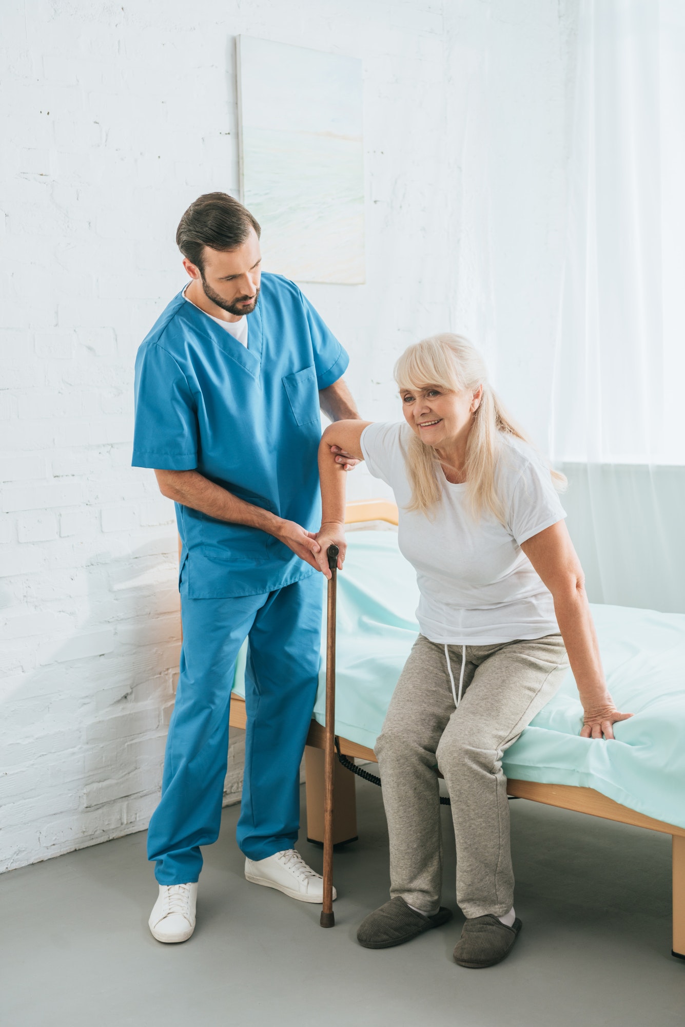 male-nurse-helping-senior-woman-with-walking-stick.jpg